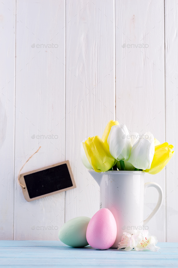 Easter invitation card with handmade painted eggs, fresh tulips bouquet and chalkboard on a duotone
