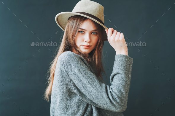 Young beautiful long brown-haired hair girl in felt hat and grey knitted sweater