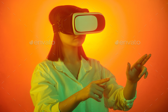 Female student in vr headset pointing at virtual display during presentation