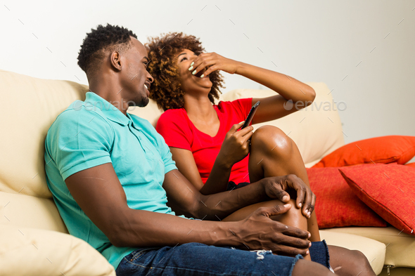 Black African American couple watching tv in the living room