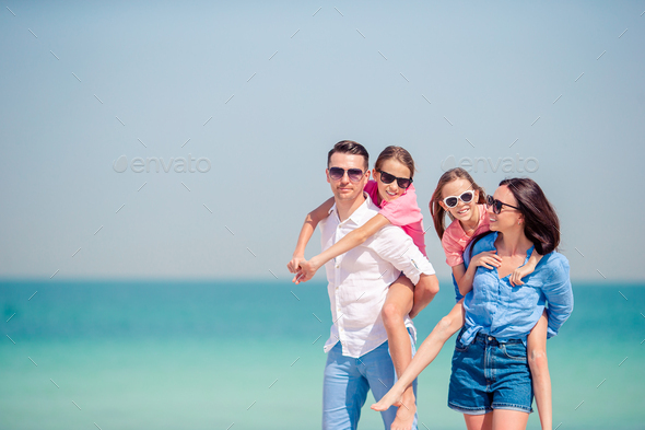 Happy family with kids on the beach together Stock Photo by travnikovstudio