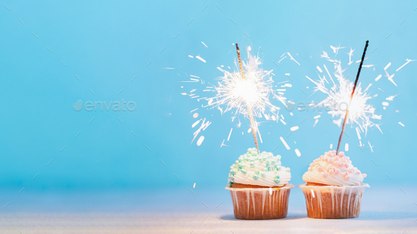 Two cupcakes decorated with sparklers, copy space