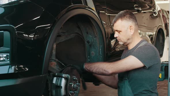 Car Mechanic Replacing Car Wheel Brake Shoes of Lifted Automobile Ac Repair alt