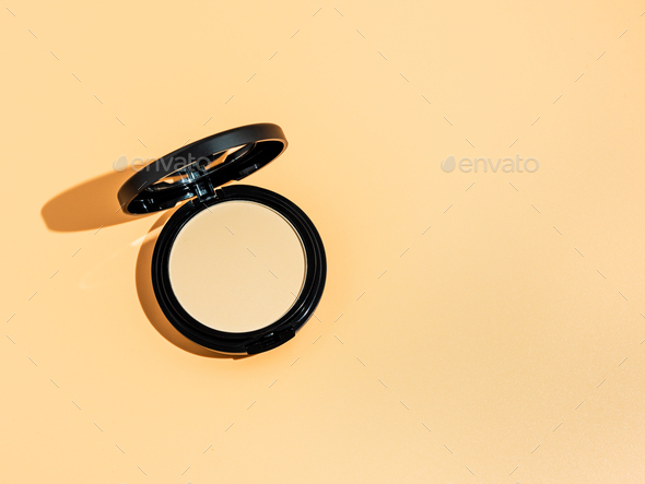 Compact powder on yellow background, copy space