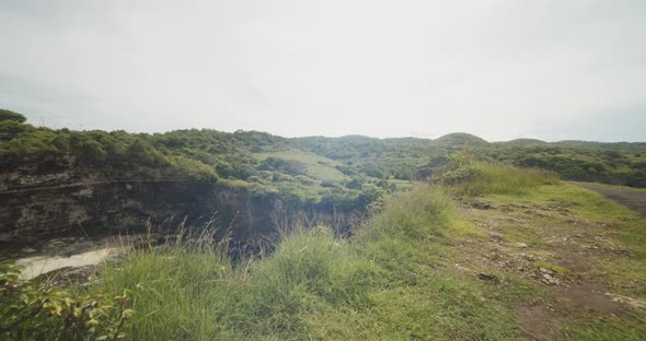Handheld Shot of Walking Along the Cliff Edge with Reveal of Stunning Sandy Beach Blue Sea and Steep alt