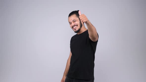 A happy Indian young adult smiling and showing thumbs up to the camera alt