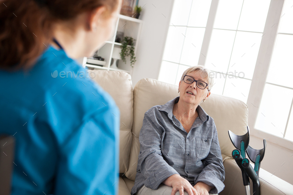 Back view of female health visitor talking with old woman