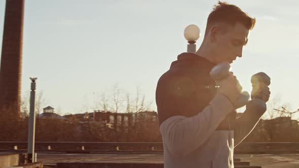 Young and fit man having evening workout outdoor. Urban sunset background. alt