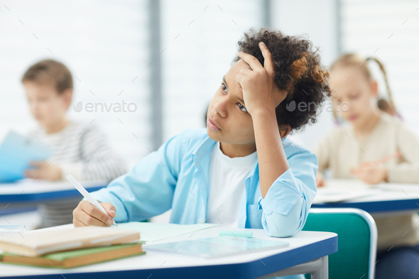 Pensive Mixed-Race Boy In Classroom