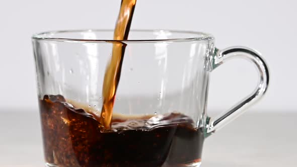 Pouring Black Coffee Into Glass Cup Over White