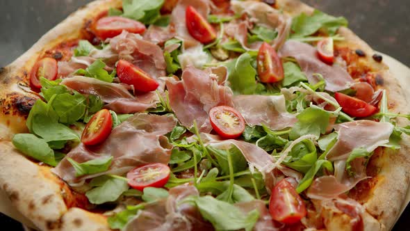 Delicious Pizza with Prosciutto Parma Ham Arugula Salad Rocket and Cherry Tomato on Rusty Dark alt