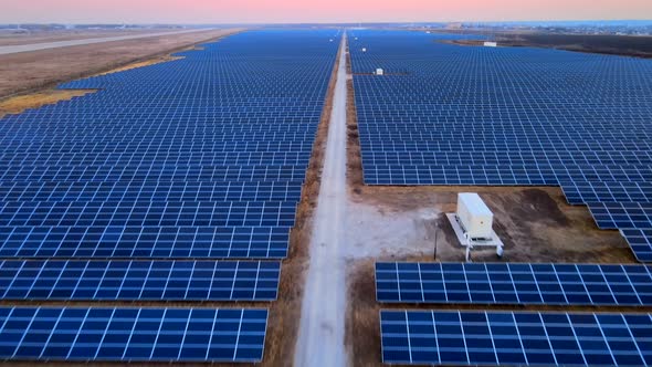 Aerial Drone View of Large Solar Panels at a Solar Farm at Bright Sunset in Early Winter alt