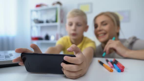 Little Male Child Playing New Cellphone Game, Mother Giving Tips to Son, Pastime