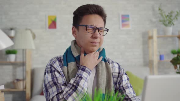 Portrait Cold Young Asian Man in a Shirt with Sore Throat Sitting at the Laptop alt
