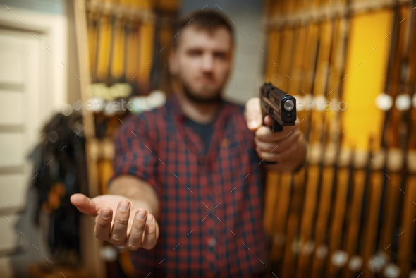 Man aims with new handgun in camera, gun shop