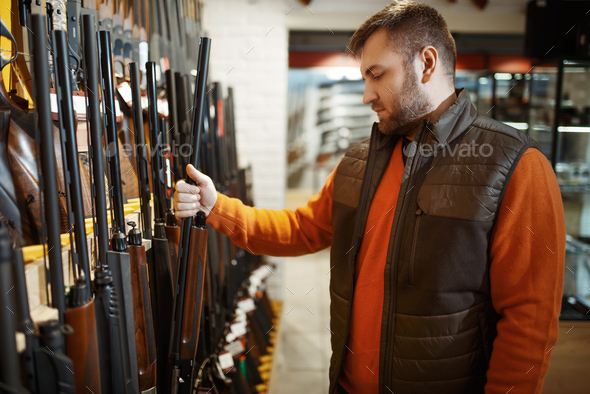 Man choosing rifle at showcase in gun shop
