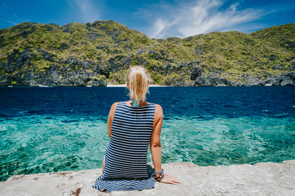 Tourist female rear view sitting on Matinloc dock pier enjoying tapiutan strait on island hoping - Stock Photo - Images