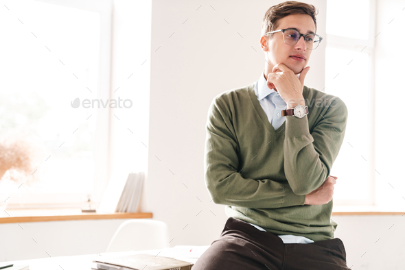 Thoughtful young guy student sit on table