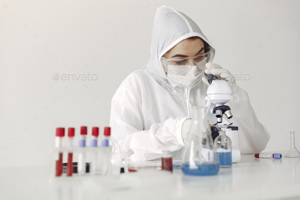 A laboratory scientist is examining blue solution in a bottle - Stock Photo - Images