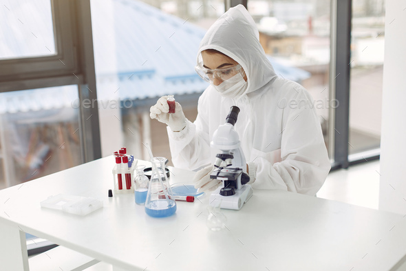 Laboratory worker in coverall suit is adjusting microscope
