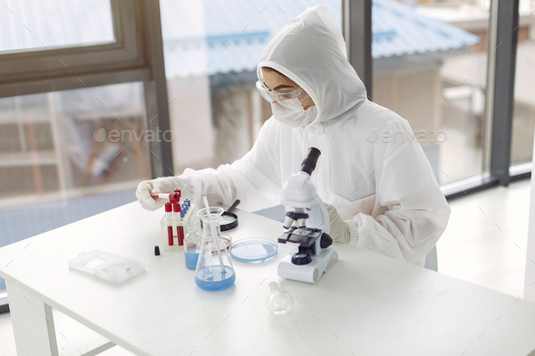 Laboratory worker in coverall suit is adjusting microscope