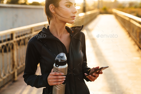 Amazing young fitness woman using mobile phone
