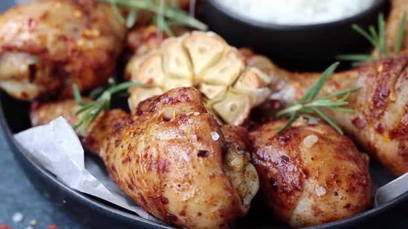 Baked Spicy Chicken Legs with Rosemary and Garlic on Black Slate. alt