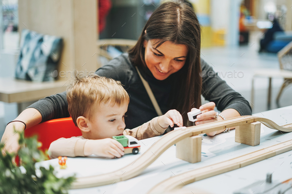 Cute baby boy toddler child with mother play with car toys in game room - Stock Photo - Images