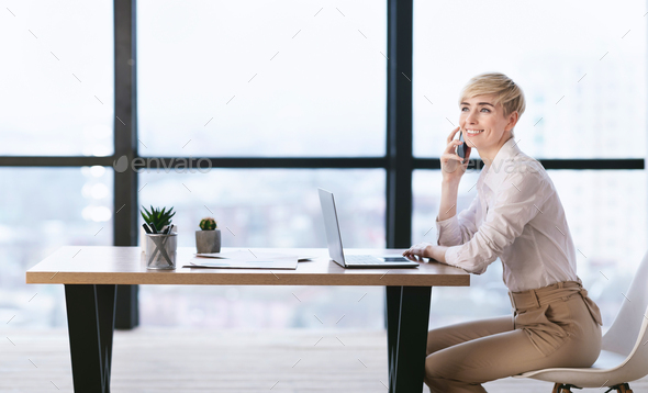 Lady Talking On Mobile Phone Sitting At Workplace In Office