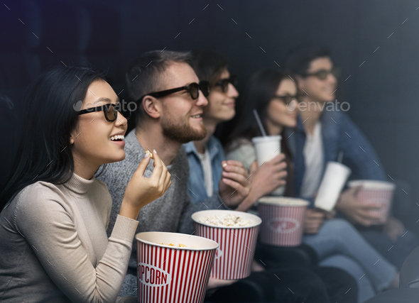 Happy people in 3D glasses watching movie in dark cinema