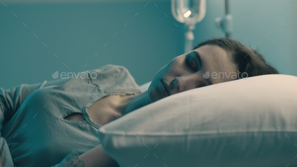 Woman lying in the hospital bed and sleeping with IV drip