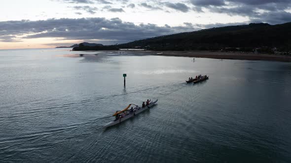 Aerial close-up shot of a team of outrigger canoes rowing across the ocean in O'ahu, Hawaii. 4K alt