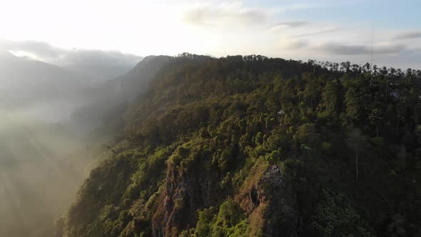 Aerial view of sunrise at mountain top with fog and clouds down in the mountain valley