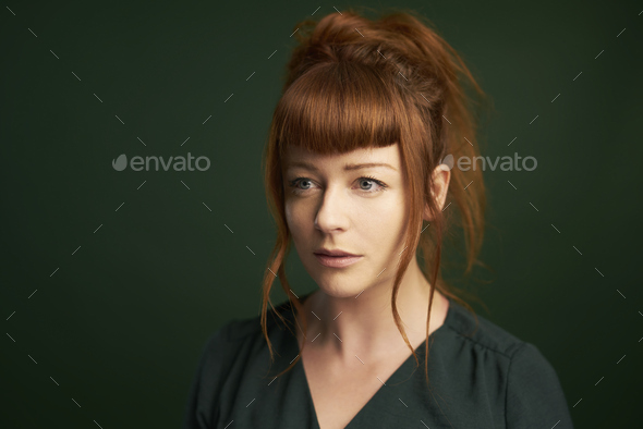 Woman with red hair and fair pale skin with green dress on green background - Stock Photo - Images
