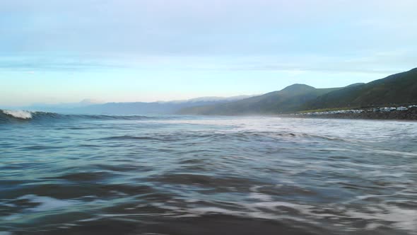 Aerial drone flying fast and low over the water surface of the Pacific ocean waves in Ventura Califo alt