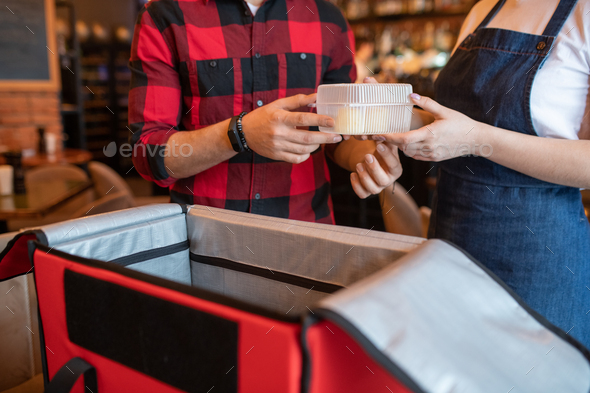 Waiter of cafe passing plastic container with order of client to courier