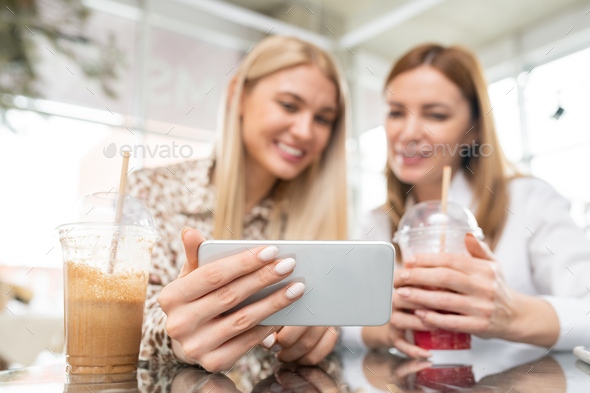 Hand of young female shopper with smartphone showing her friend online goods