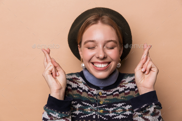 Photo of pretty pleased woman in earrings smiling with fingers crossed