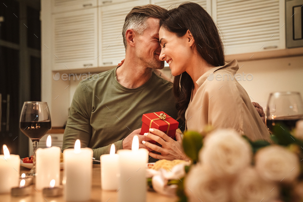 Image of man giving present box to his girlfriend during romantic dinner