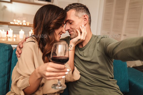Image of couple taking selfie while having candlelight dinner at home