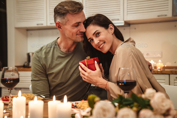 Image of man giving present box to his girlfriend during romantic dinner