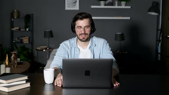 Business man freelancer agent call manager wears headphones head microphone looks into laptop alt