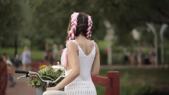 Woman in White Dress Looking at Camera While Riding in Park