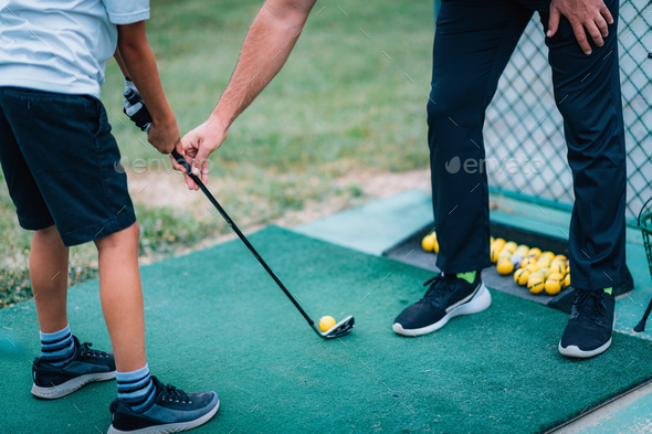 Golf Lessons. Golf instructor giving game lesson to a young boy.