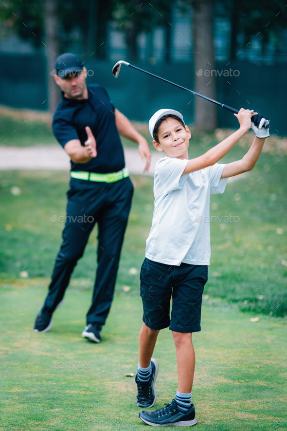 Personal Golf Lessons. Golf Instructor Adjusting Swing of a Young Boy.