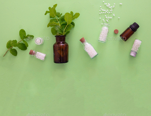 Homeopathy, globules and herbs on green background Stock Photo by rawf8