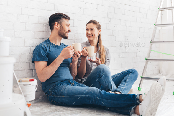 Happy young couple having rest while sitting in new apartment