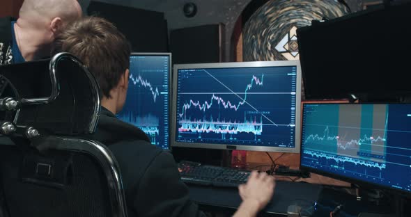 Two Man Traders on Stock Exchange Discussing Charts of Falling and Rising Quotes