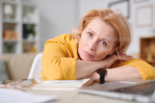Mature blond self isolated businesswoman looking at you while lying on desk