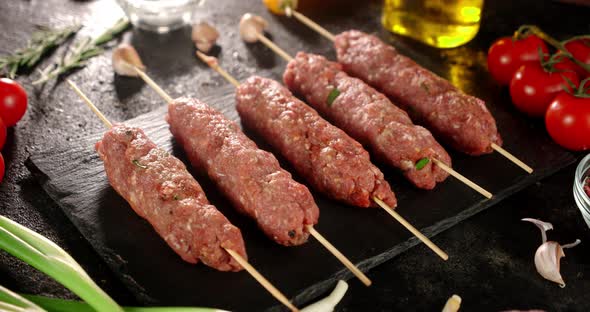 Raw Kebab Sausages on a Stone Board Rotate.  alt
